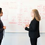 homme et femme debout devant un tableau blanc